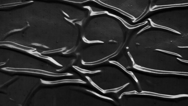 Abstract black wrinkled plastic texture background, dark crumpled surface with light reflections