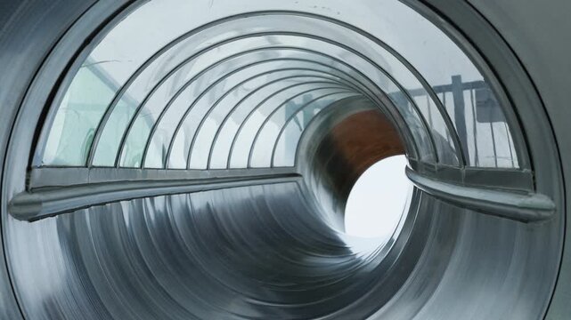 Looking out from inside a spiral metal playground slide tunnel.