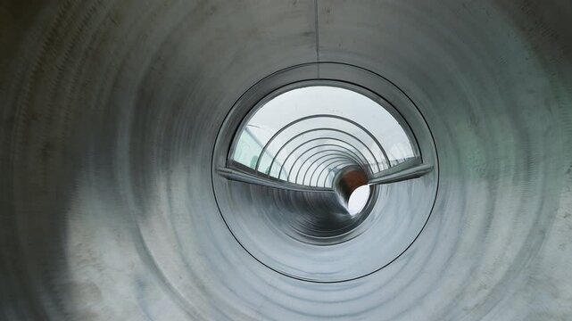 Geometric perspective looking down a curved silver metallic tube.
