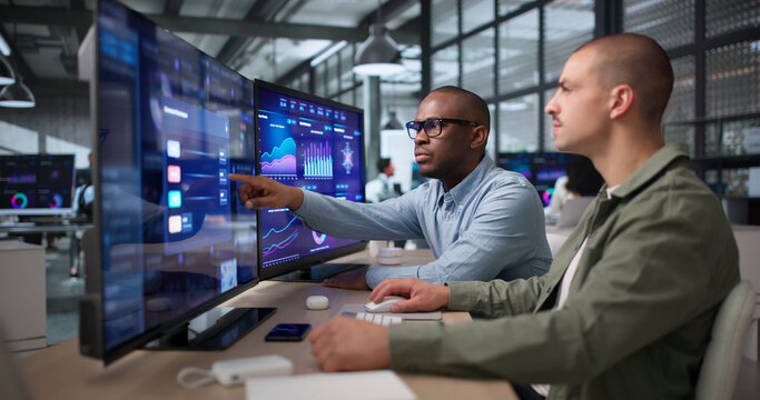 Two Young Data Analysts Reviewing Financial Dashboard