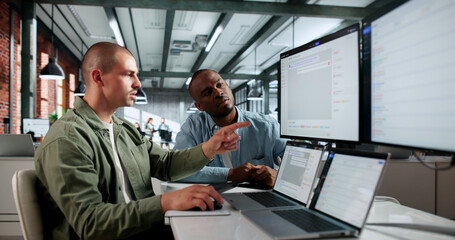 Two African American IT Service Managers Discuss Incident Tickets