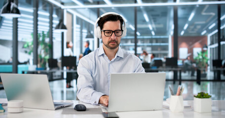 Fototapeta premium Focused Man Manages Two Laptops