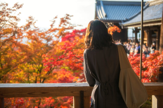 Tourist woman view autumn leaf in Kiyomizu-dera temple at sunset, Kyoto
