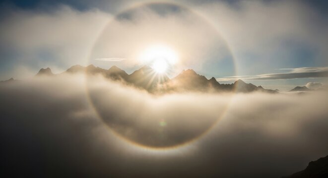 Sun halo above misty mountains during sunrise
