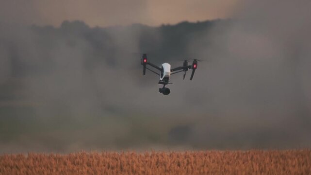 Unmanned aerial vehicle inspects crops at dusk, Autonomous drone surveys wheat fields during evening dusk hours
