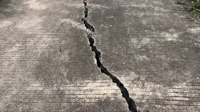 Severely cracked concrete road surface with deep fissure
