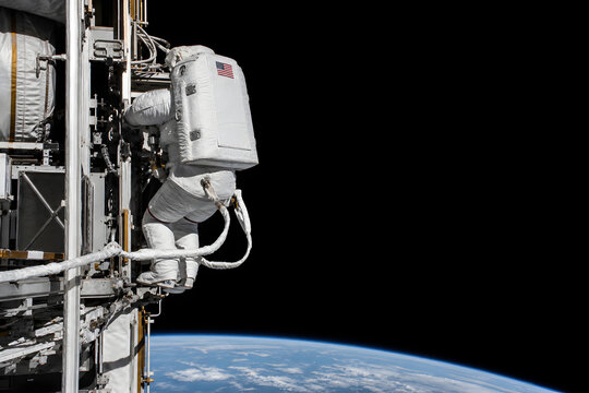 Astronaut tethered outside station above Earth horizon