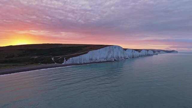 Aerial view of the iconic Seven Sisters white chalk cliffs during a vibrant sunset with purple clouds over the English Channel Exceat, England, United Kingdom.