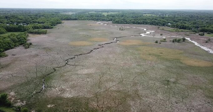 Aerial drone video of a very dry patch of grassland wit a crack in the ground forming a creek path on agricultural land. 