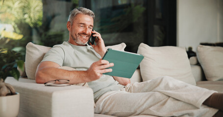 Phone call, smile and tablet for remote work with man on sofa in home living room as freelancer. App, conversation and research with mature person in apartment for report or review as happy employee © peopleimages.com