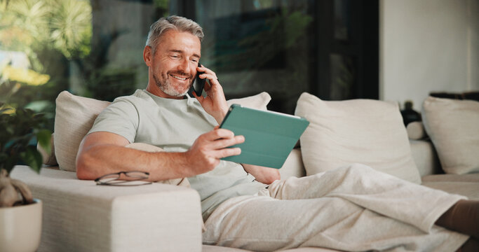 Phone call, smile and tablet for remote work with man on sofa in home living room as freelancer. App, conversation and research with mature person in apartment for report or review as happy employee
