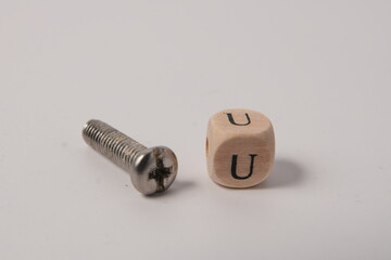 Fototapeta premium Single Metal Screw and Wooden Cube with Letter U for Connection Concept on White Studio Background