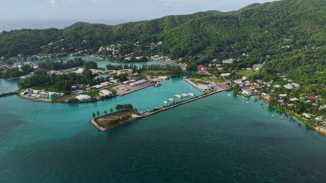 Aerial view of Praslin Ferry Harbour with boats docked in turquoise waters surrounded by lush green hills in Baie Ste Anne, Baie Sainte Anne, Seychelles.