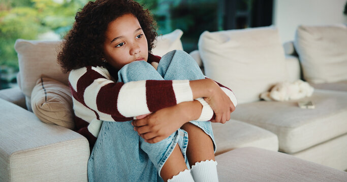 Lonely, child and thinking on sofa, home and girl with low self esteem from bullying or bad memories. Remember, trauma and kid with anxiety, sadness and reflection on insecurity and mental health