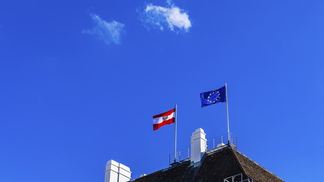 The Austrian national flag and the flag of the European Union fly over the Federal Chancellery, Ballhausplatz, Vienna, Austria