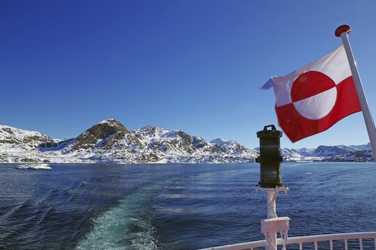 Greenland national flag and coastal landscape with snow, winter, Greenland, Denmark