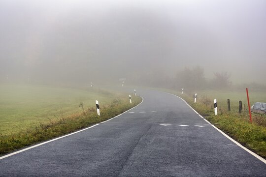 Curvy road to K&ouml;terberg, speed limit markings on roadway, shark's teeth, dreary autumn weather with fog, L&uuml;gde, Weserbergland, North Rhine-Westphalia, Germany