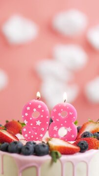 Birthday cake candle number 98. Vertical video of candle and cake on pink background and fire by lighter. Close-up and slow motion
