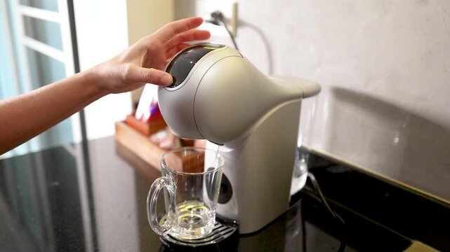 Person Operating a Modern Capsule Coffee Machine in a Kitchen