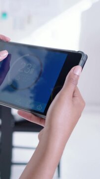 Vertical video: woman's hand adjusting tablet temp in studio, designer in beige top arranging notes