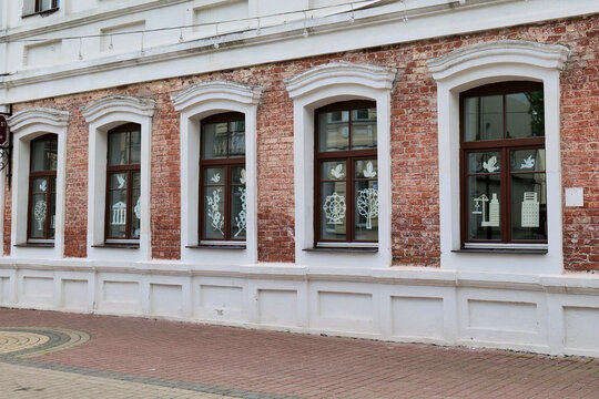 Red brick building facade with two windows and white window sills in urban setting