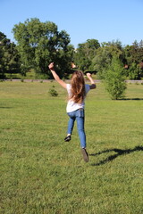Fototapeta premium Happy Young Girl Jumping in the Air on a Green Grass Field