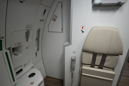 An empty flight attendant jumpseat next to an exit door inside an airplane cabin.