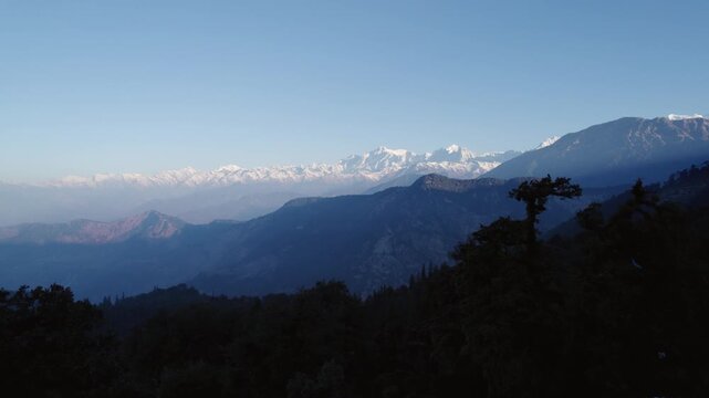 Aerial view of the snow-capped Himalayan mountain range and dense forests near Chopta Tungnath in Chopta, Uttarakhand, India.