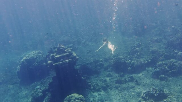 Freediver girl swimming underwater towards the seabed