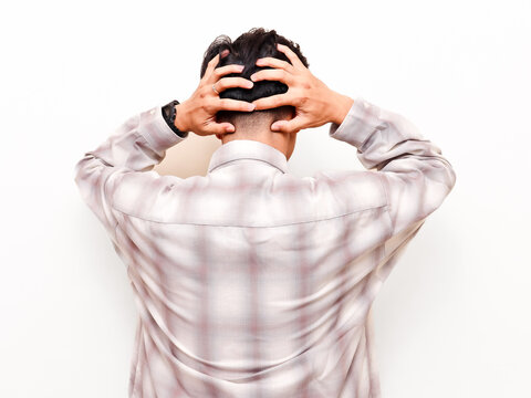Back view of stressed Asian businessman grabbing his head showing frustration and anxiety, corporate burnout concept isolated on white background