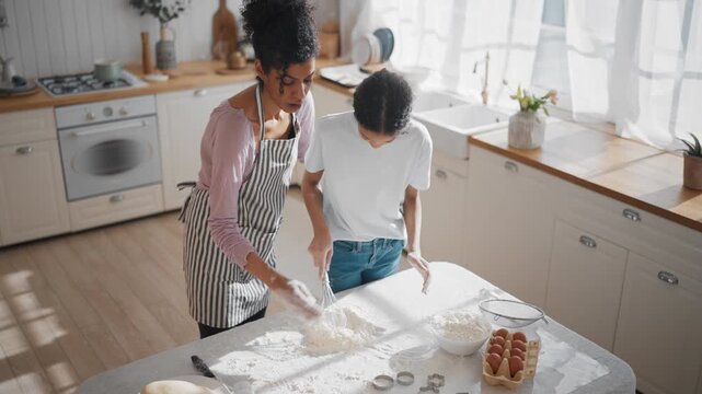 African american woman and daughter making dough from organic gluten-free flour. Culinary master class for adolescent and teenager, mother teaching teen girl to cook. Family dinner, homemade bakery