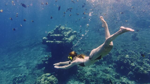 Woman snorkeling underwater exploring a sunken shrine