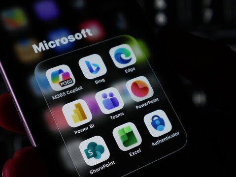 Closeup of a smartphone screen displaying various microsoft application icons including m365 copilot, bing, edge, teams, and powerpoint