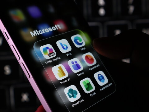 Closeup of a smartphone screen displaying various microsoft application icons including copilot, bing, edge, teams, powerpoint, power bi, excel, and authenticator