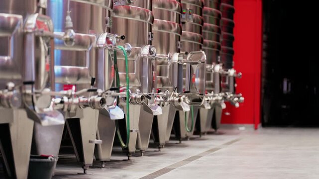 Shiny steel fermentation tanks lined up in winery for wine production process.