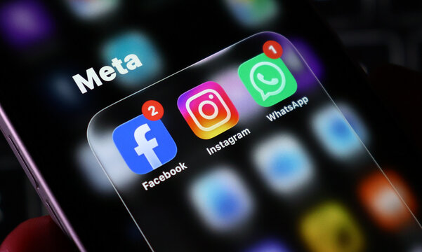 Closeup of a smartphone screen displaying the meta app group folder containing facebook, instagram, and whatsapp icons with notification badges