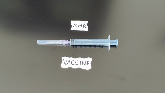 Measles, Mumps and Rubella childhood disease prevention and protection immunity vaccination or injection concept. Hand placing syringe near MMR vaccine word or text.