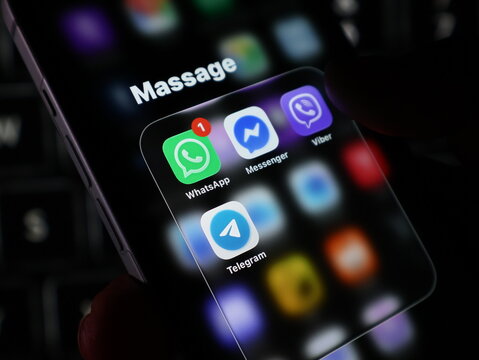 Closeup of a smartphone screen displaying popular messaging apps like whatsapp, messenger, viber, and telegram in a dark environment