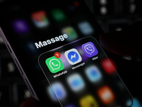 Closeup of a smartphone screen displaying messaging apps like whatsapp, messenger, and viber with a notification badge, held by a persons hand