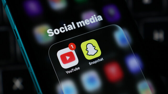 Closeup of a smartphone screen showing social media app icons including youtube and snapchat with a notification badge