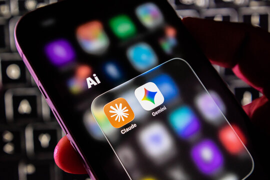 Closeup of a smartphone screen displaying artificial intelligence app icons including claude and gemini in a folder labeled ai
