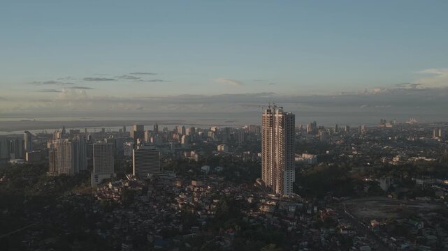 Aerial view of Cebu City skyline with high-rise buildings and dense urban housing under a soft evening sky Cebu City, Central Visayas, Philippines.