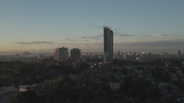Aerial view of the urban skyline with a tall skyscraper under construction and dense residential areas in Cebu City, Central Visayas, Philippines.