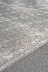 Fototapeta premium An eye level perspective shows a worn gray asphalt surface covered with patterns of fading white traffic markings or paint.
