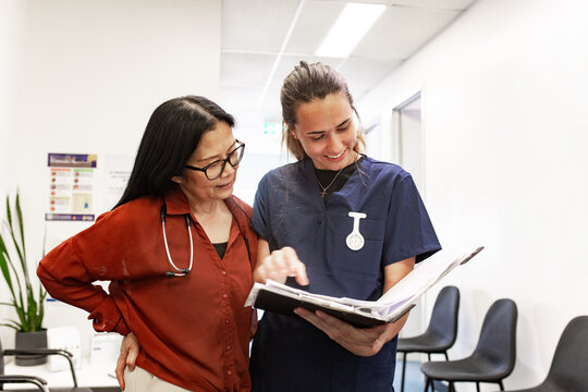 Healthcare professionals reviewing patient chart in clinic hallway