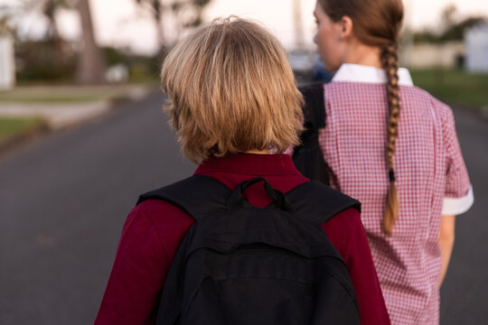 two children walking with school uniform and with school bags