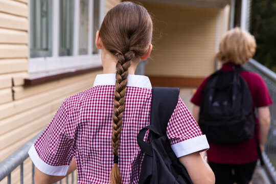school girl with a long plait and back pack outside a building