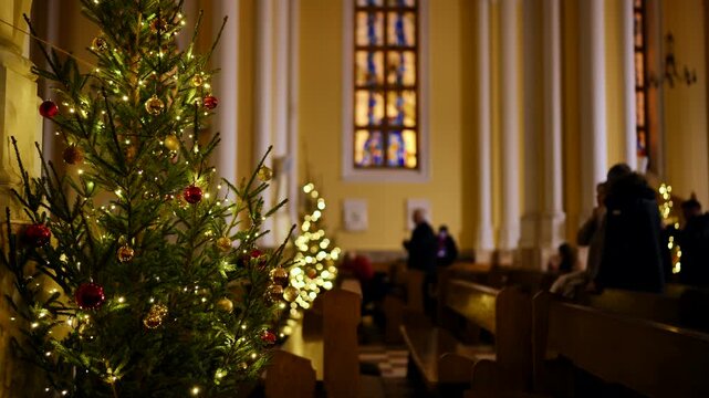 Christmas tree glowing inside a Catholic Church, parishioners attending mass