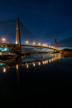Vertical view of the iconic Barelang Bridge illuminated during blue hour before sunrise with perfect water reflections in Batam, Indonesia