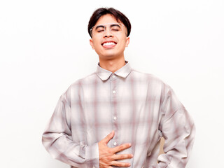 Happy young Asian man holding his stomach with satisfied smile, feeling full or relieved from stomachache isolated on white background © Muhammad Alimaki